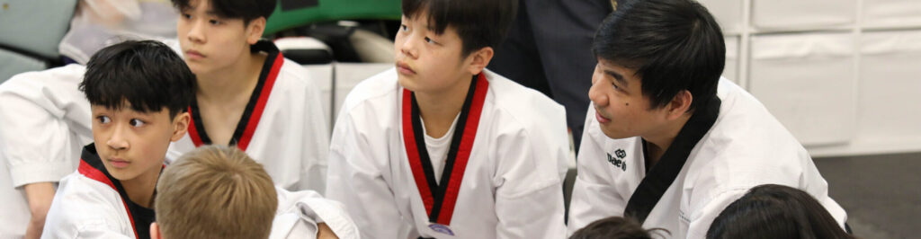 Group of Endurance Taekwondo students listening attentively to instructor during class
