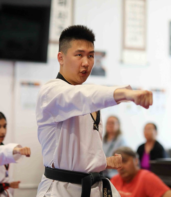 Young adult black belt throwing a sharp punch in class