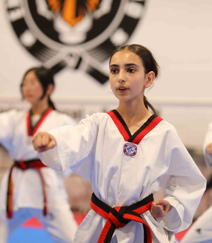 Three teen students punching in unison, one girl in front