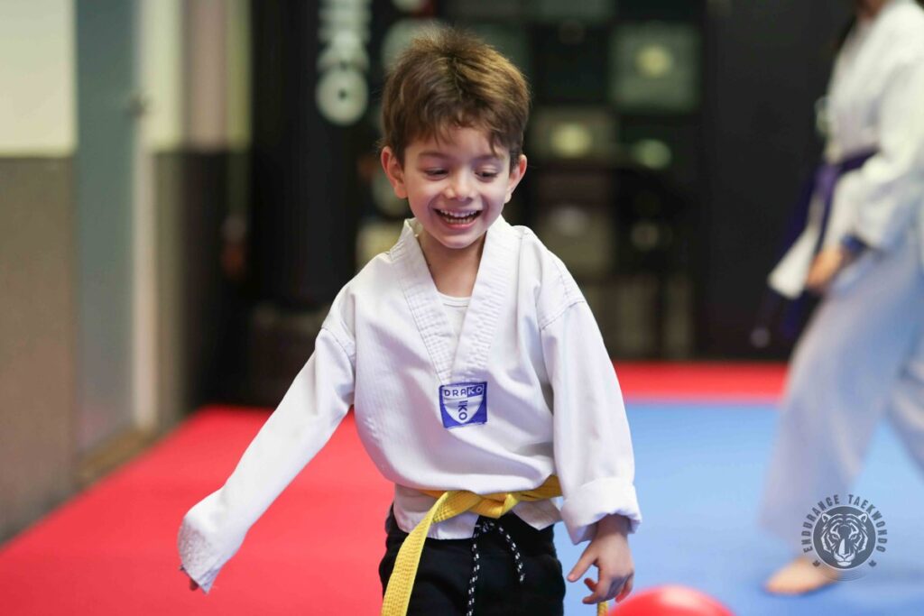 A yellow belt boy laughing during a game at taekwondo camp