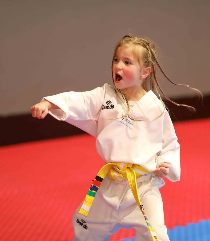 Little girl with braids throwing a punch with a full kihap (the shout) at her colour belt test