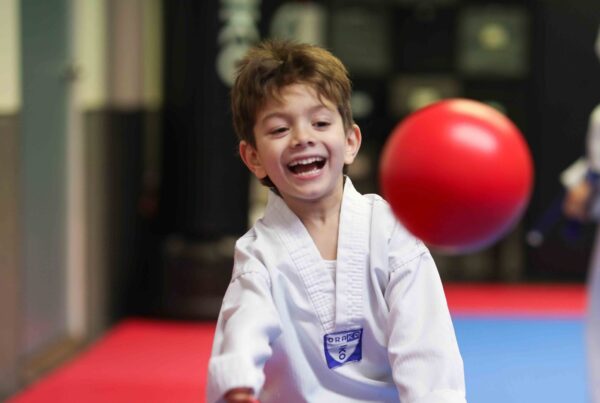 Smiling boy playing dodgeball at Endurance Taekwondo spring break camp