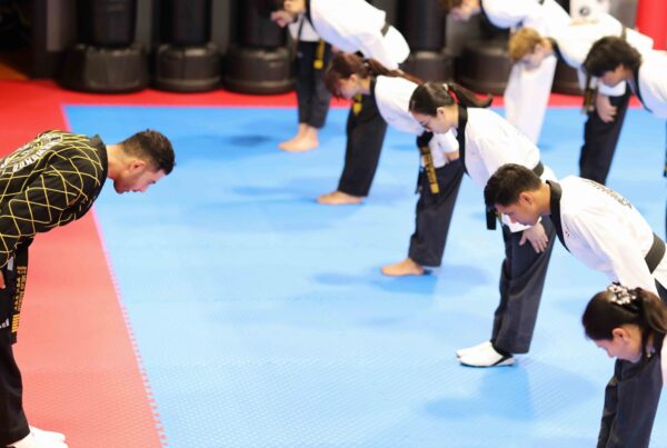 Taekwondo students bowing to their master on the blue mat at Endurance Taekwondo