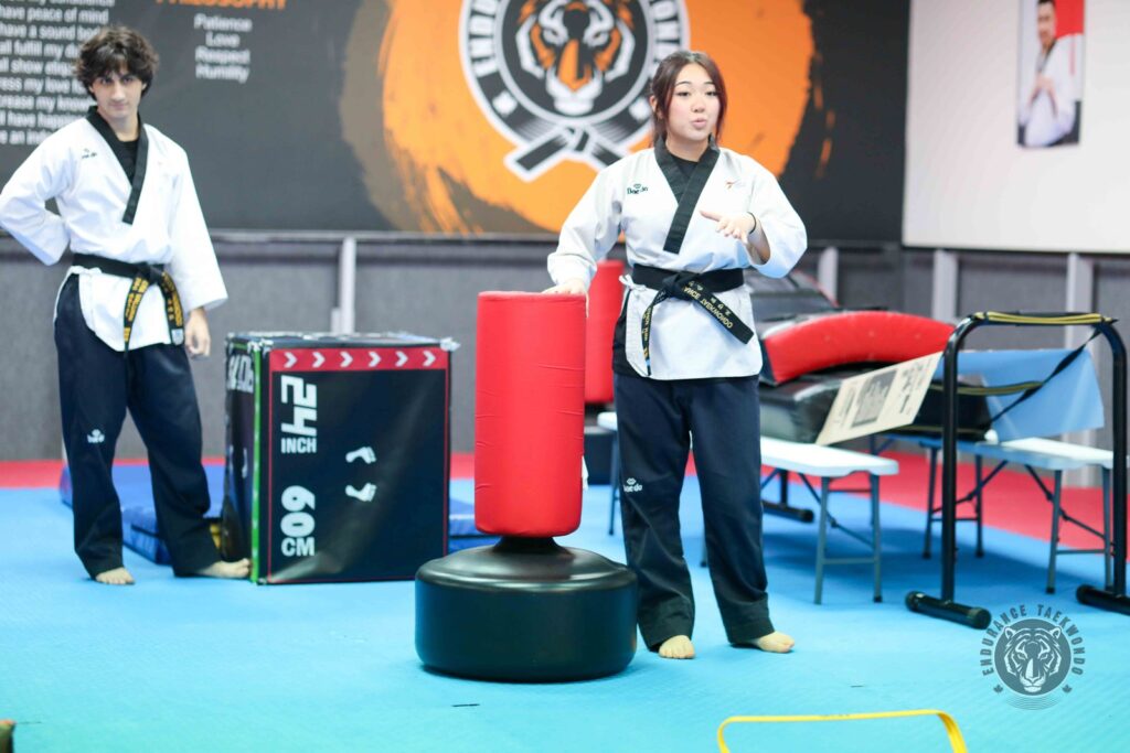 Two teen black belt leaders explain a training station to younger students